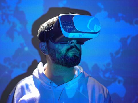 A man with a VR headset with a blue world map in the background