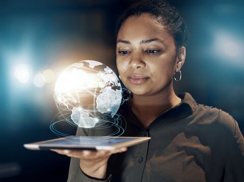 A woman holding a digital representation of the globe with illuminated network connections spanning across it