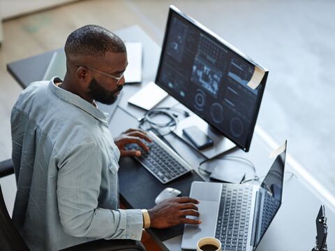 A man analyzing data on multiple screens in a high-tech office setup