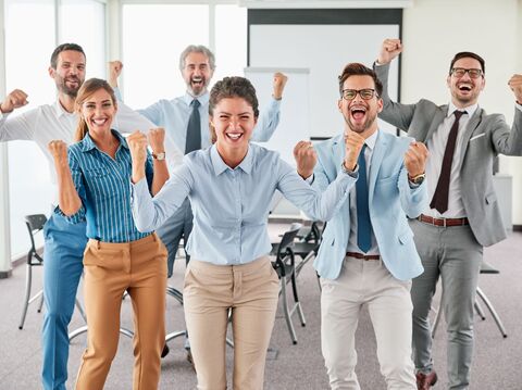 six people in a corporate meeting setting cheering and standing up