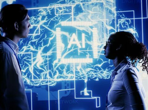 Two people, a man and a woman, stand facing each other with a digital interface between them. The interface features a glowing blue background with the letters \"AI\" prominently displayed, surrounded by neural network-like patterns and technological graphics