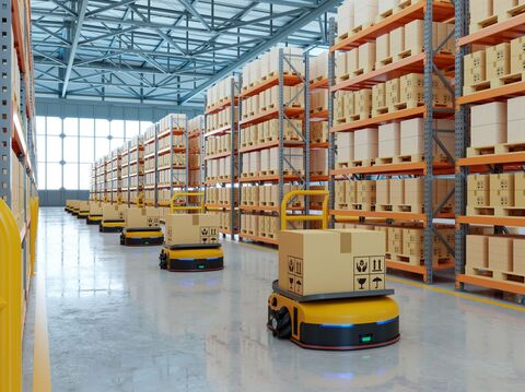 A picture of a warehouse with yellow rovers carrying a package in a straight line