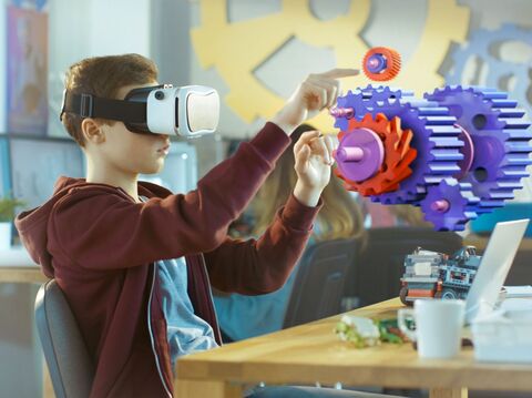 Young boy in hoodie interacting with virtual gear mechanisms through VR headset