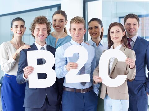 A group of people standing and holding the big capital letters of B2C