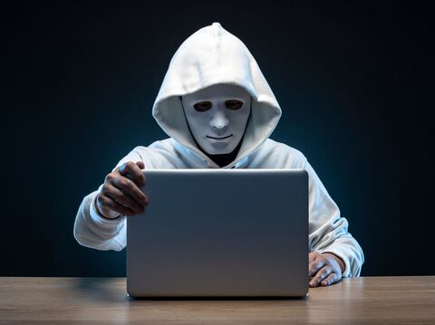 A person with white face mask and white jacket closing a laptop