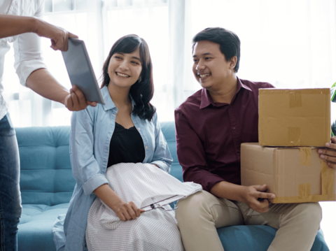 Couple receiving a tablet delivery while holding boxes, smiling