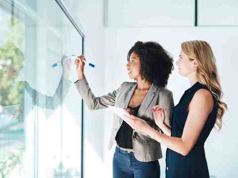 Two woman on a glassboard discussing ed tech