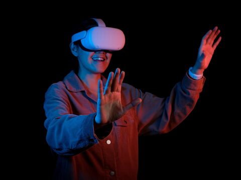 A woman wearing virtual reality glasses, striking a pose while immersed in virtual reality