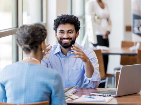 A man with curly hair in a blue shirt having a discussion