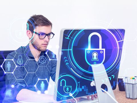 A man working on a computer with holographic lock and security icons, representing cyber security concepts