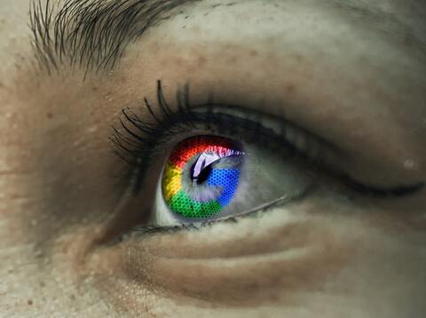 Close-up of a human eye with a rainbow colored iris. The eye appears to be looking directly at the viewe