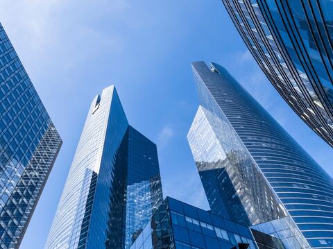 A cluster of skyscrapers with modern glass and steel exteriors reaching towards a clear blue sky