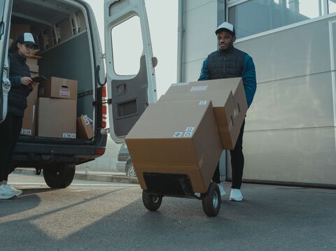 A logistics van with two workers showing carrying packages for delivery