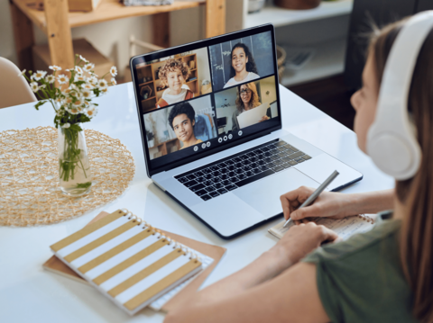 Young girl participating in an online class with peers on laptop