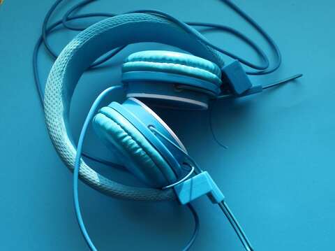 A pair of blue headphones resting on a flat blue surface