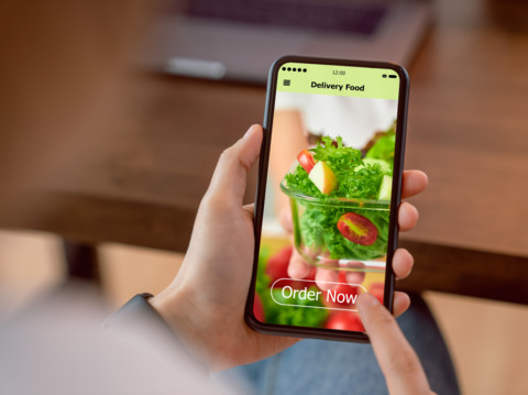 A person holding a smartphone with a food delivery app open on the screen