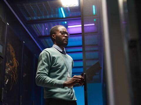 IT professional in a server room with blue and purple lighting, emphasizing data center operations