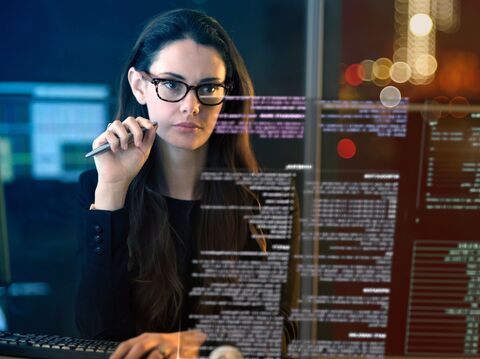 A focused female programmer coding intently, surrounded by computer screens