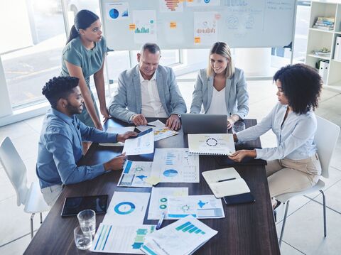 A group of people in a meeting room, sitting on chairs, and having discussion on some data charts