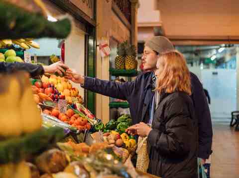 A couple examining fresh produce at an outdoor market stall