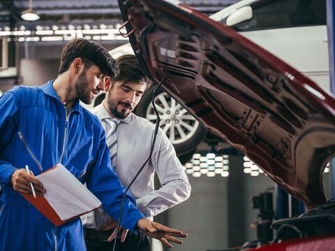 Two mechanics inspecting a vehicle in an auto repair shop