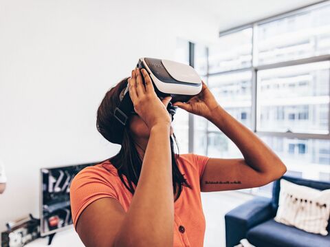 A woman in an orange shirt using a virtual reality headset in a modern office