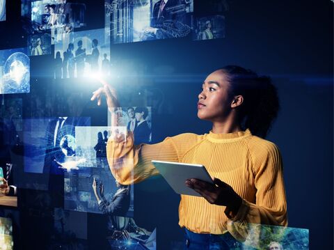 A woman is tapping some augmented reality images with her finger and holding a tab in the other hand.