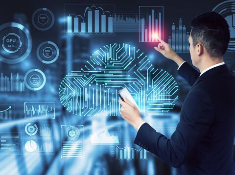  A businessman in a suit interacts with a virtual data dashboard, featuring a cloud-shaped circuit board design, various graphs, and performance indicators for CPU, GPU, and memory usage. The background is a blurred office setting, emphasizing the digital data analytics environment