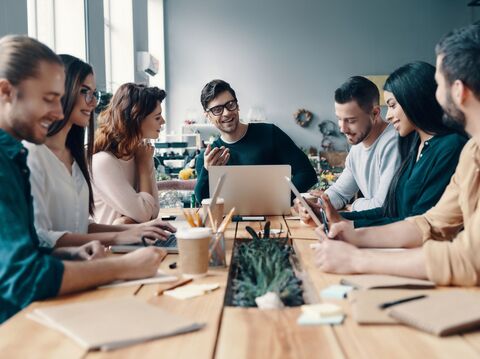 seven people in a round table with a person guiding them through the meeting