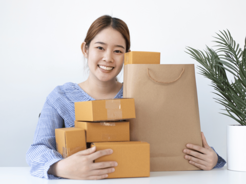 Young woman smiling while holding shopping bags and cardboard boxes