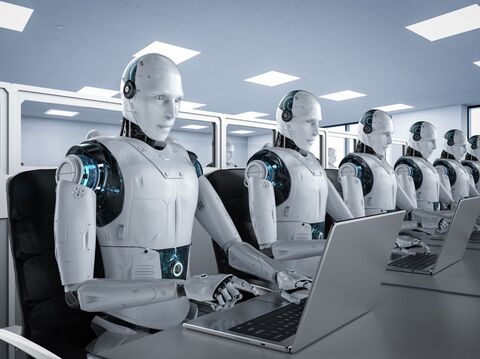 A row of humanoid robots seated at desks, each operating a laptop in a modern office environment