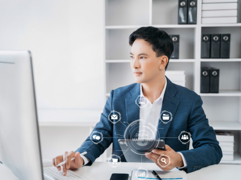 Businessman at a modern office desk, interacting with a digital marketing interface on his computer