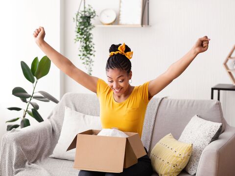 Happy woman celebrating while unboxing a package in her living room