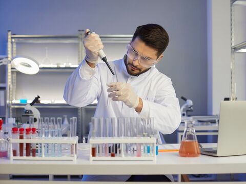 Male scientist in lab coat pipetting samples in modern laboratory