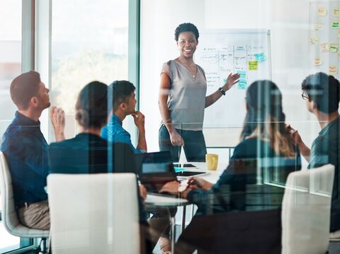 Diverse group of professionals engaged in a strategic discussion around a glass table in a bright office