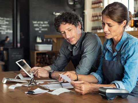 Two middle-aged restaurant owners analyzing data on a tablet