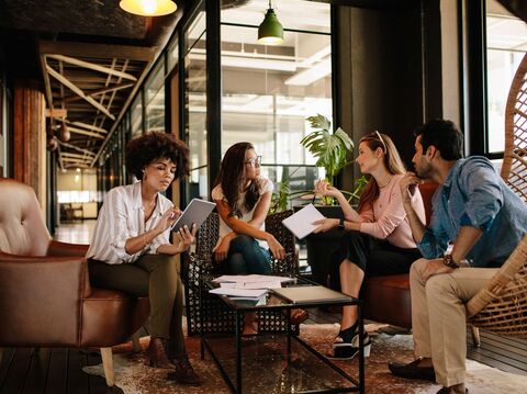 Group of four diverse professionals in a casual meeting in a modern lounge