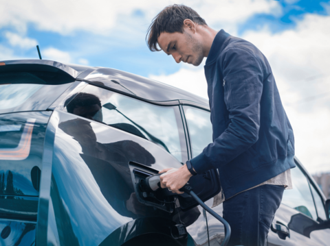 Man charging an electric vehicle at a charging station