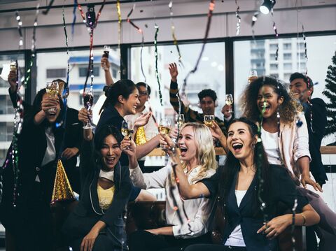 A diverse group of office colleagues celebrating with champagne and confetti in a brightly lit office space, showing joy and camaraderie