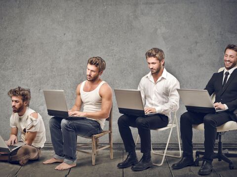 Four men in different stages of office attire and grooming, from casual to formal, using laptops to depict the evolution of workplace norms