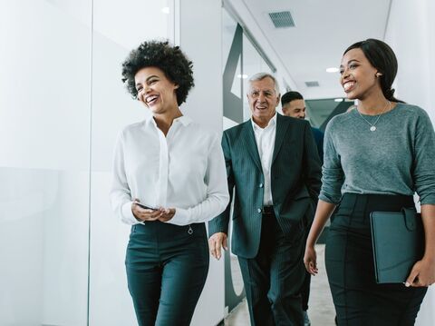 four people coming to a meeting room while chatting in the hallway