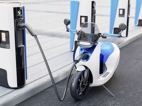 An electric scooter plugged into a charging station