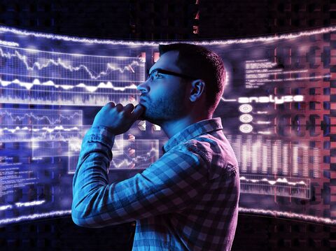 A man observing multiple digital screens displaying data and analytics