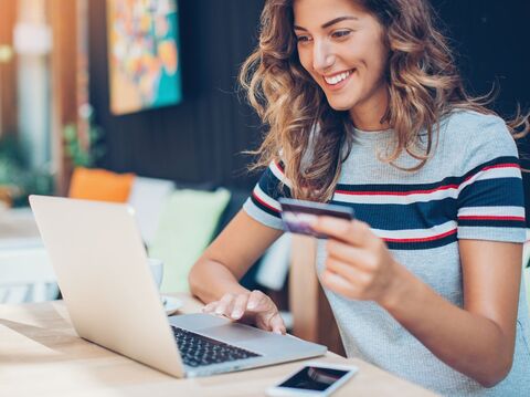 A woman buying things online with her credit card while browsing products on her laptop