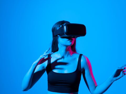 A woman experiencing virtual reality with a VR headset, against a blue background