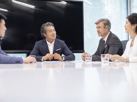 A group of business professionals engaged in a meeting around a conference table in a modern office setting