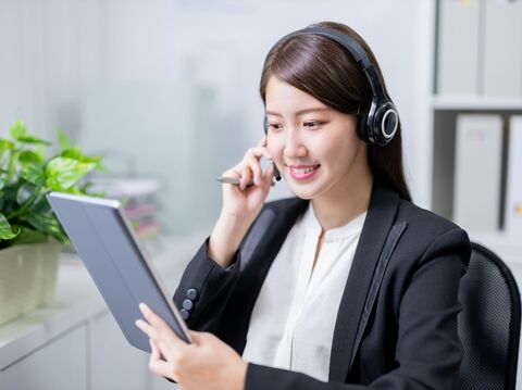 A professional woman wearing a headset, smiling, and interacting with a tablet, symbolizing video-based customer service