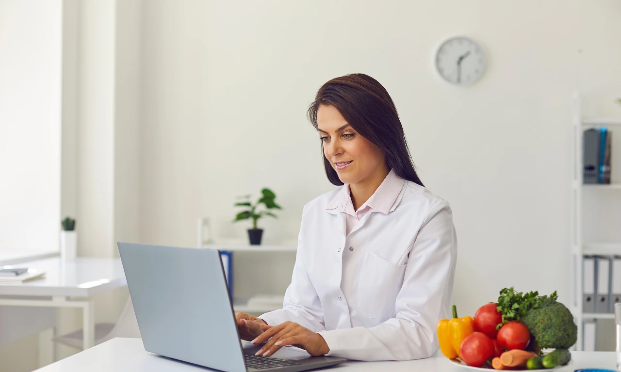 Female healthcare professional using a laptop for digital health consultation and wellness management in a clinical setting