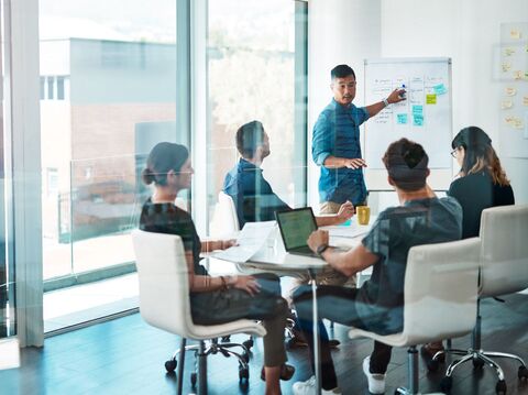 In a meeting room, a young man is presenting some data to the people present in the room