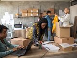  Team working on e-commerce tasks surrounded by boxes in a small office